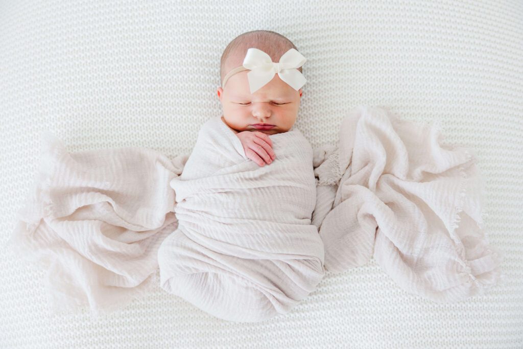 newborn baby with wrap on white backdrop at the white room.