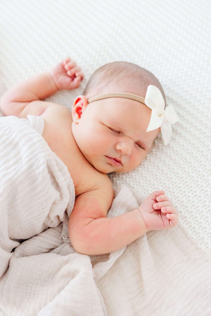 Newborn baby girl with her fists up on either side. 