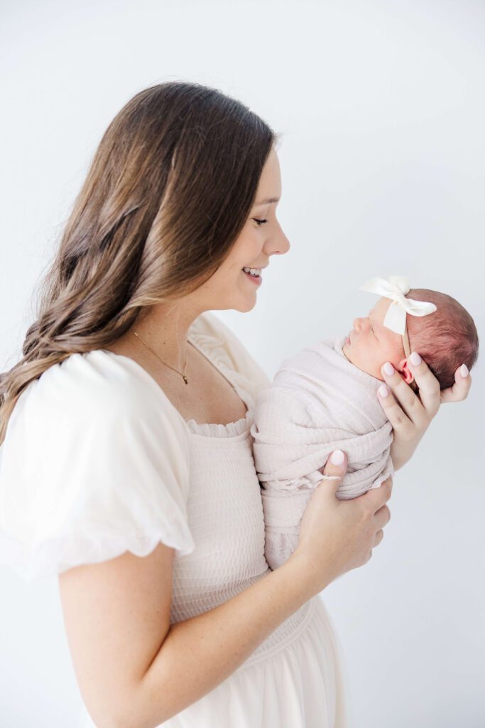 Mom and Newborn looking at each other with a bow on.