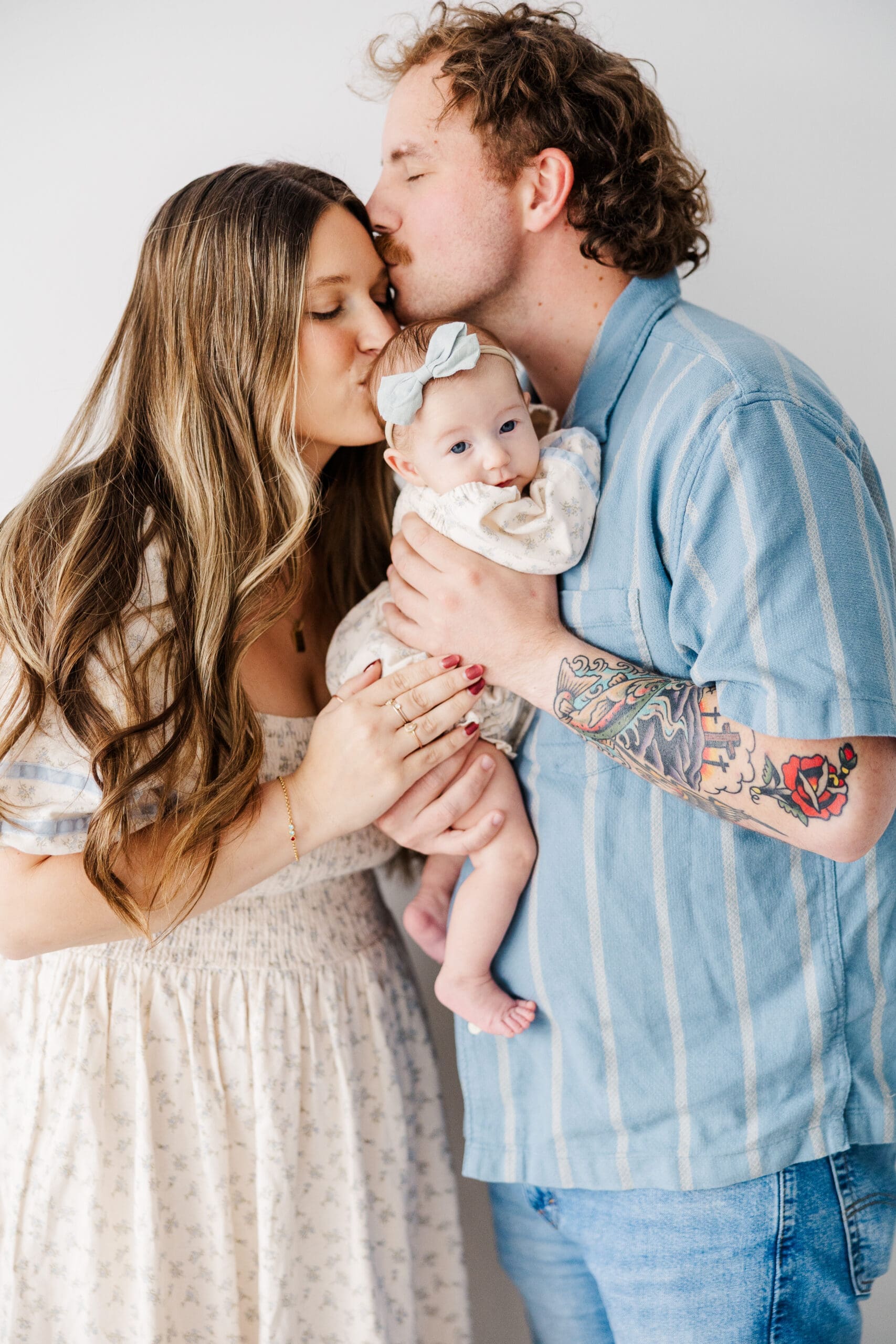 family together; dad kissing moms forehead and mom a kissing babys' forehead