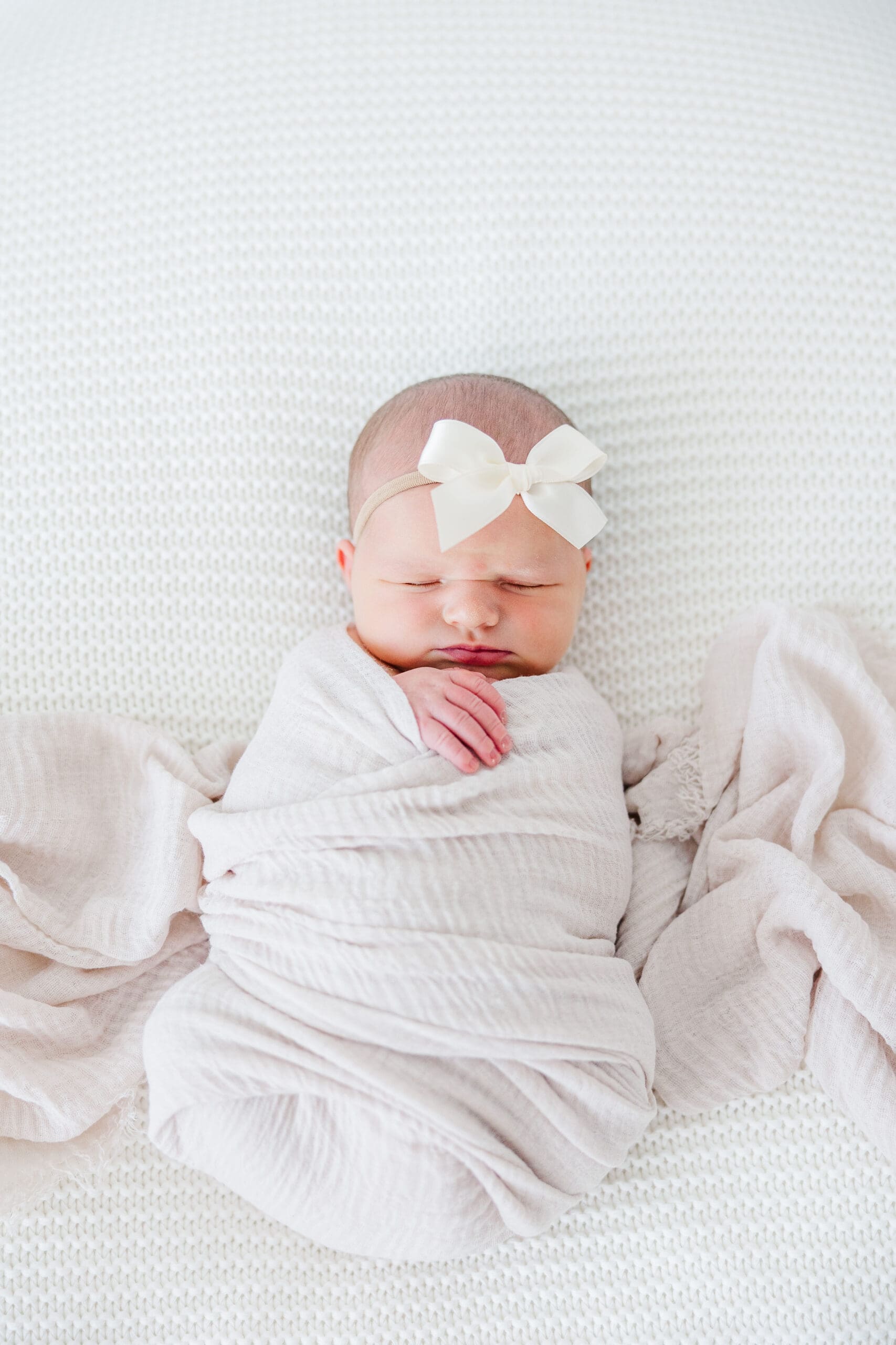 baby girl swaddled with bow