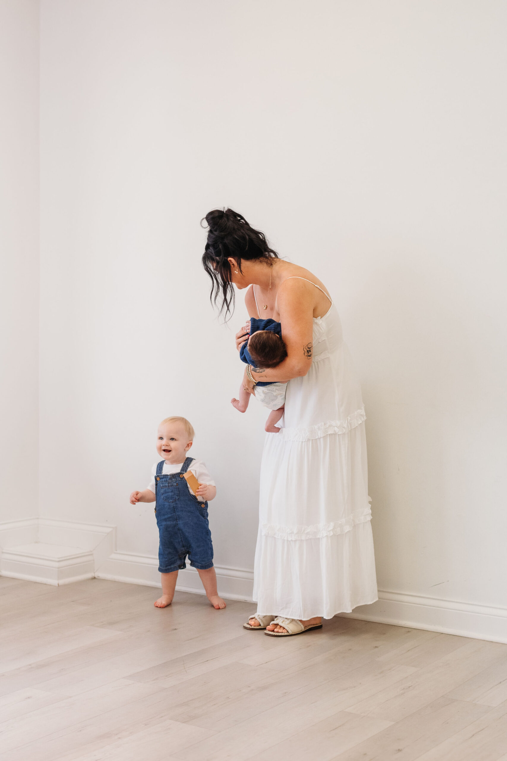 mommy playing with her children against a white wall at the white room